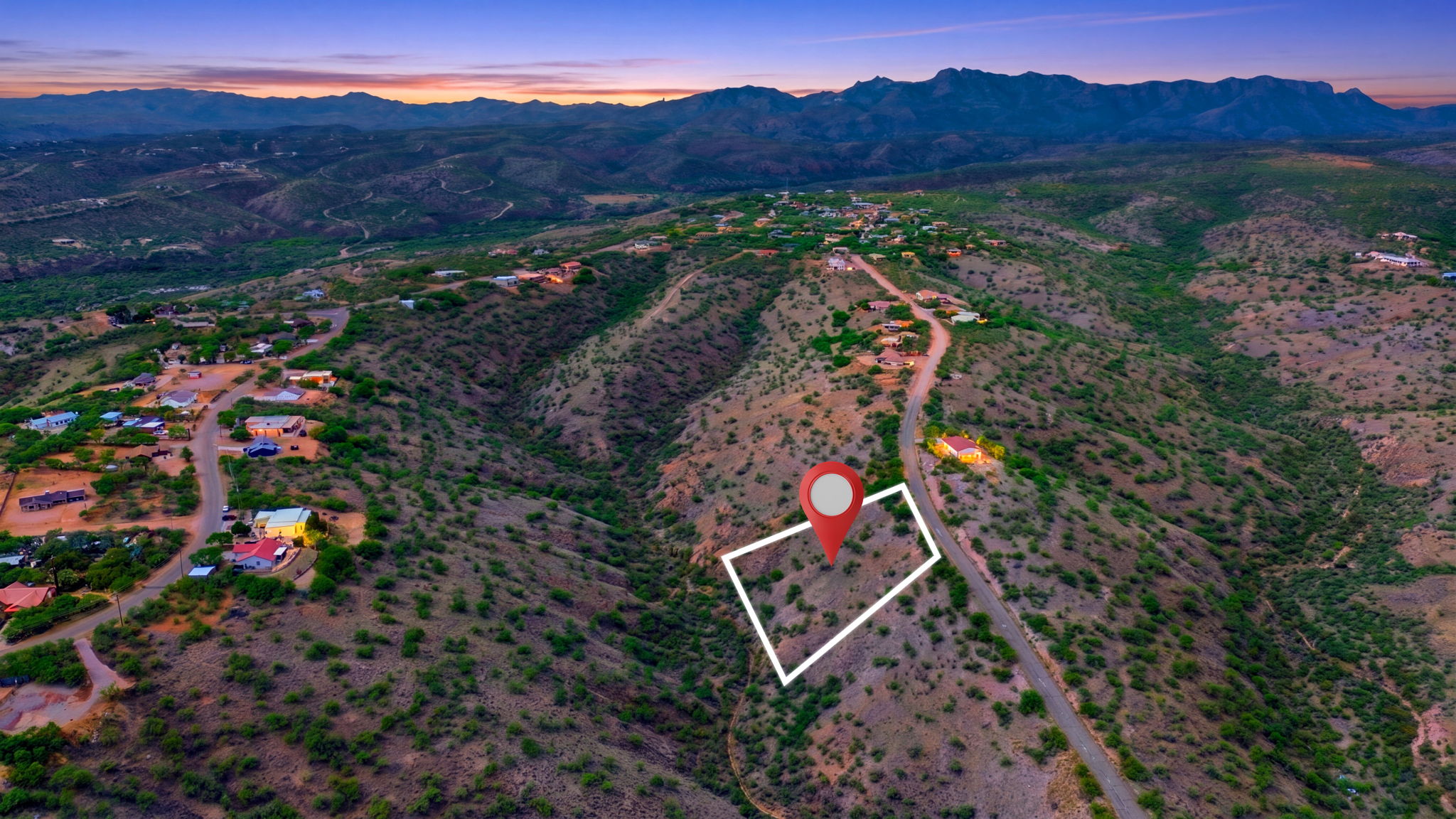 Small desert parcel marked with an outline beneath mountain views at dusk