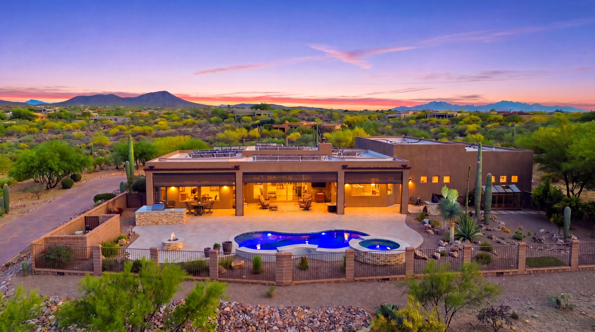 Aerial view of a luxury desert home and blue pool at dusk