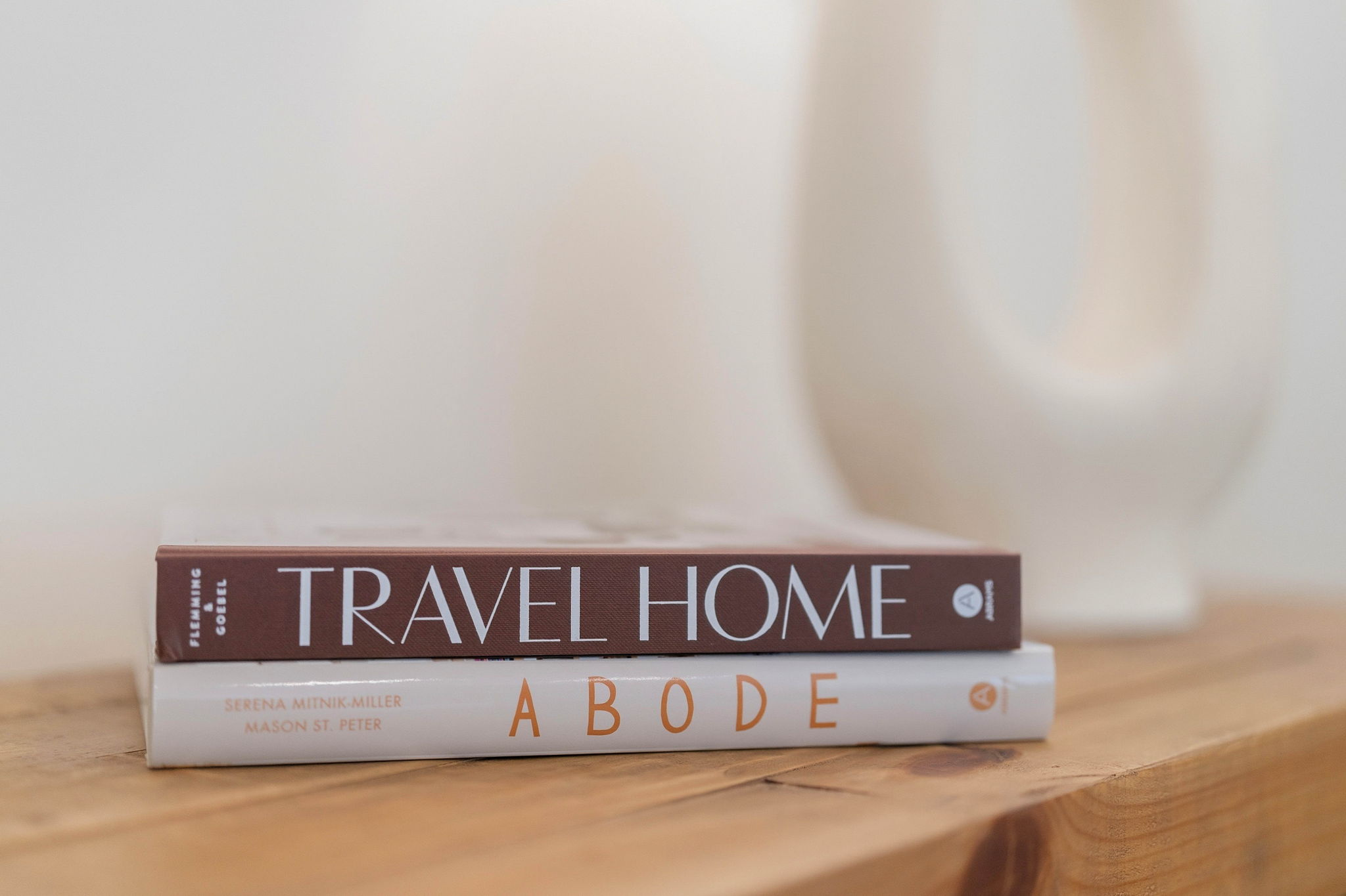 Travel Home and Abode books beneath a white lamp