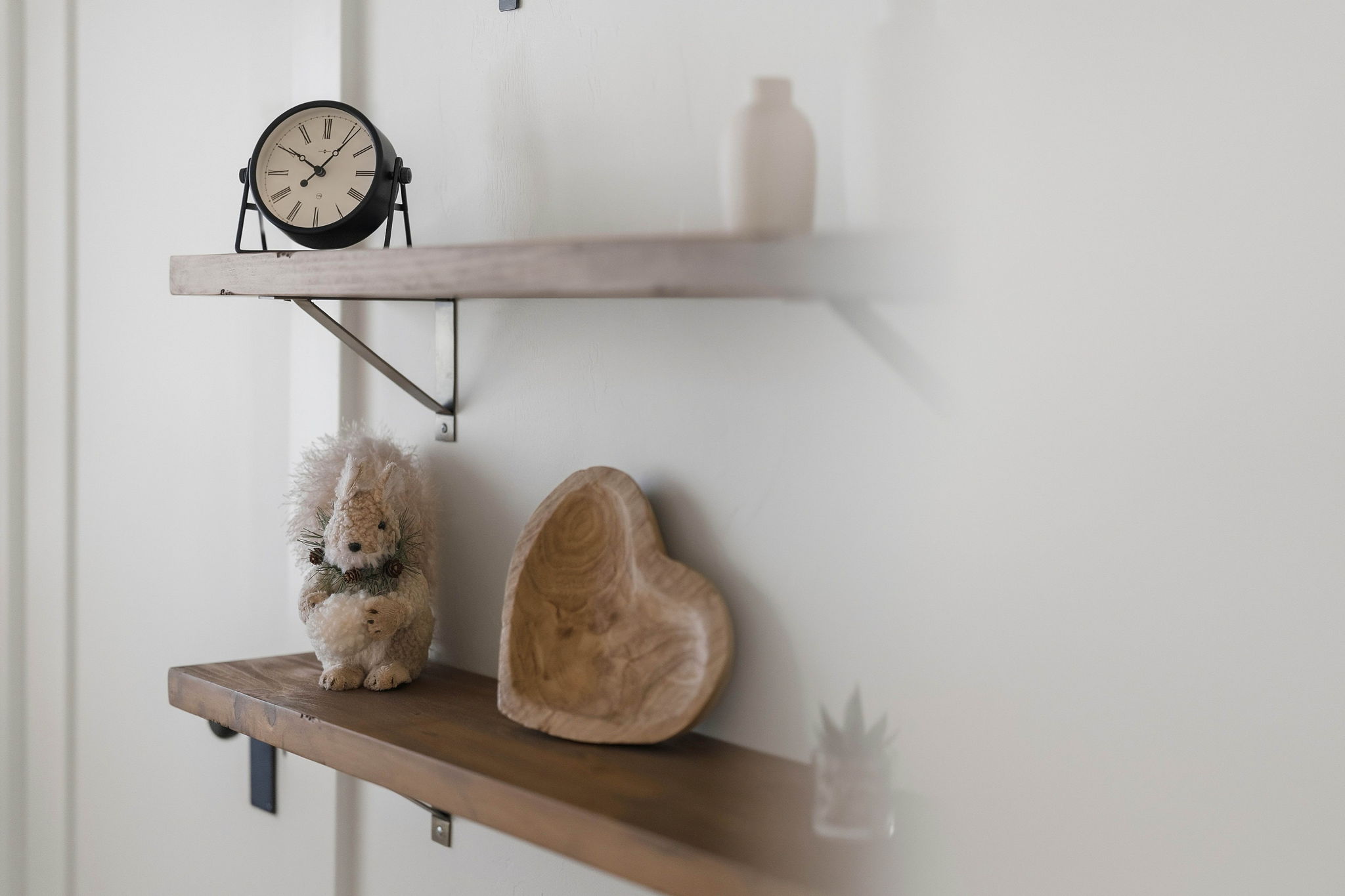 Clock and carved wooden heart displayed on floating shelves