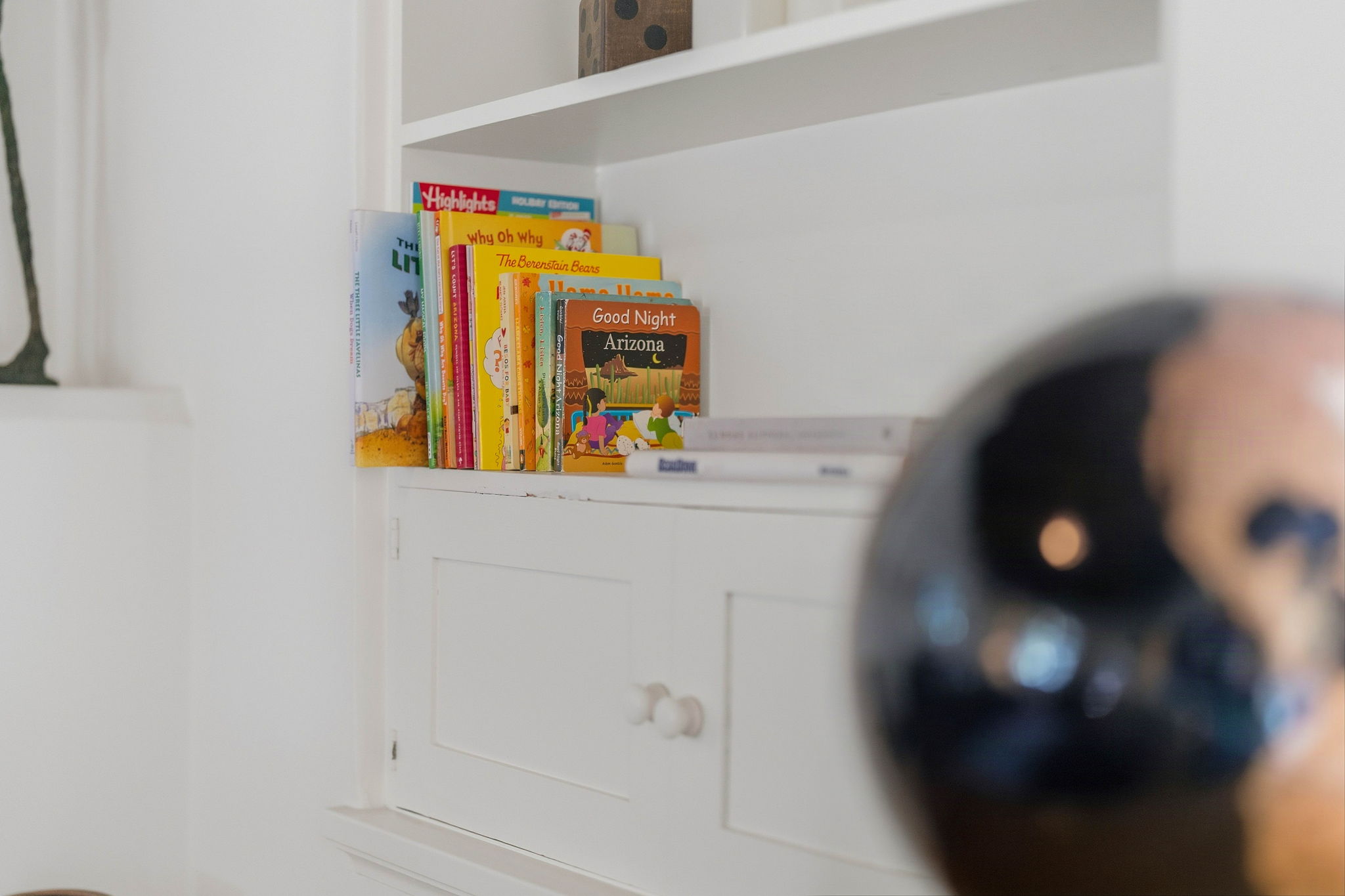 Children’s books on white shelves with a globe in the foreground
