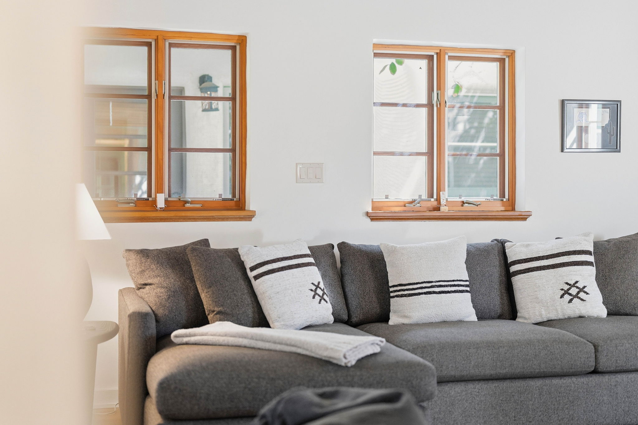 Gray sectional with Southwestern pillows beneath wood-framed windows