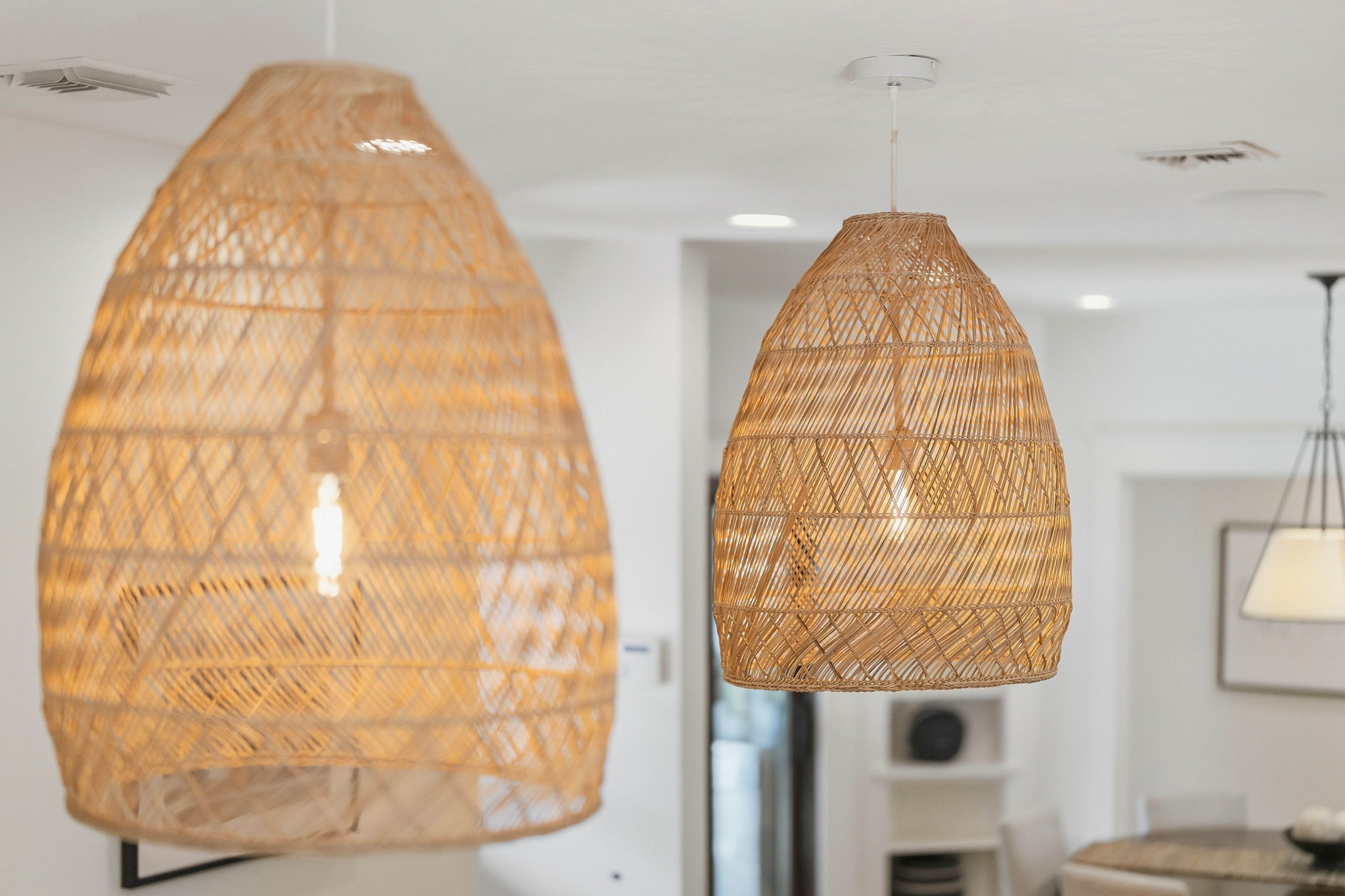 Glowing woven pendant lights in an airy dining space