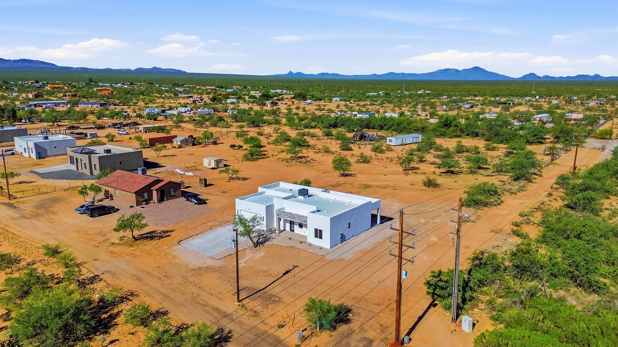 Aerial view of a newly built home on a desert lot with surrounding homes and mountains