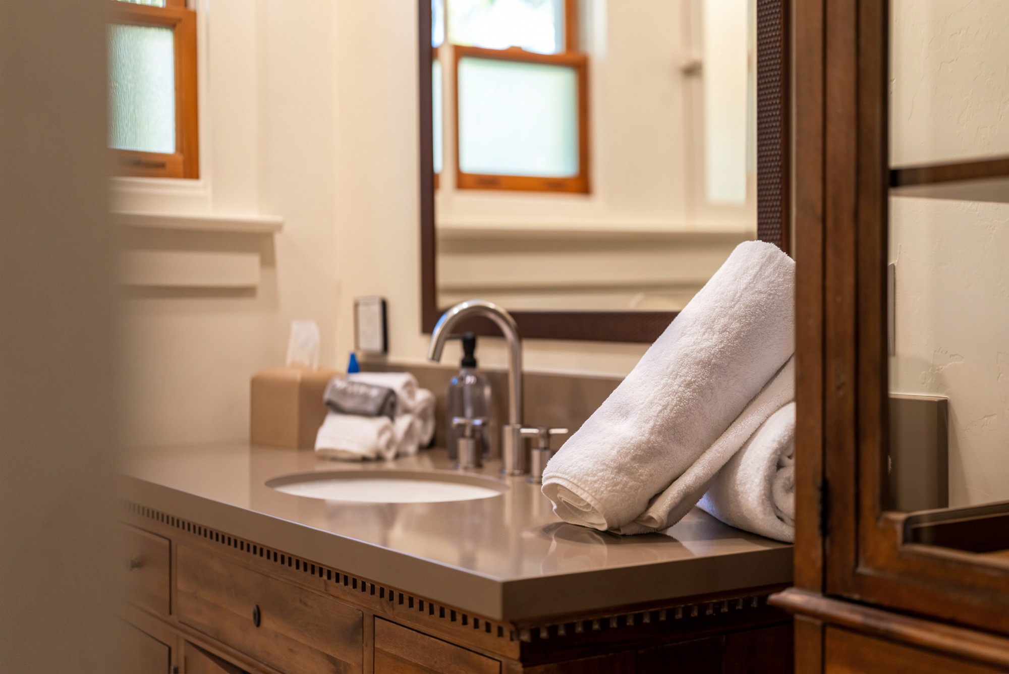 Folded white towels beside a bathroom sink and framed mirror