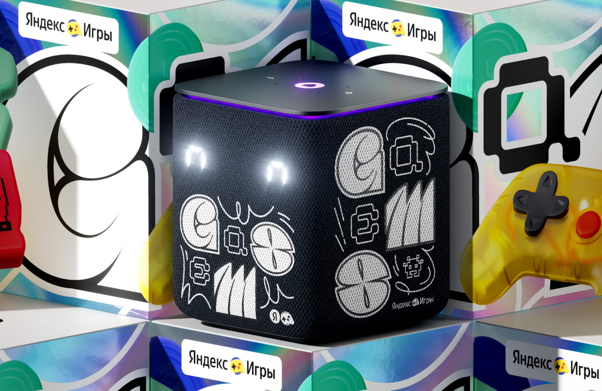 Black cube-shaped smart speaker with glowing eyes and graphic doodles on its surface, surrounded by colorful gaming-themed images and Russian text.