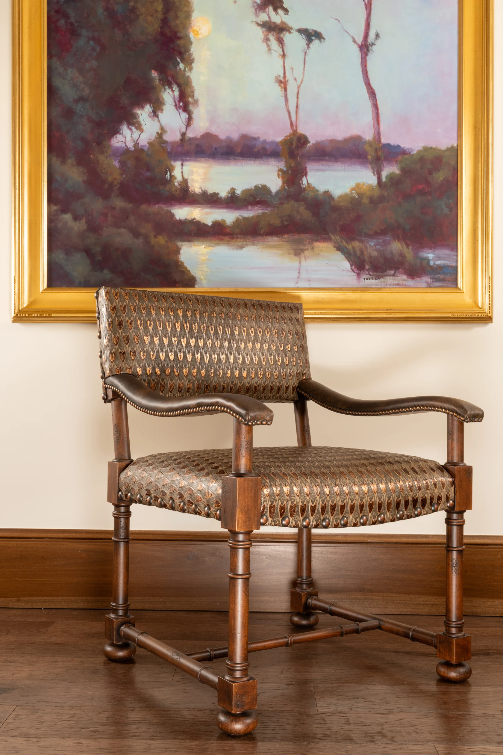 A carved wood armchair with patterned upholstery and fine brass nailhead trim