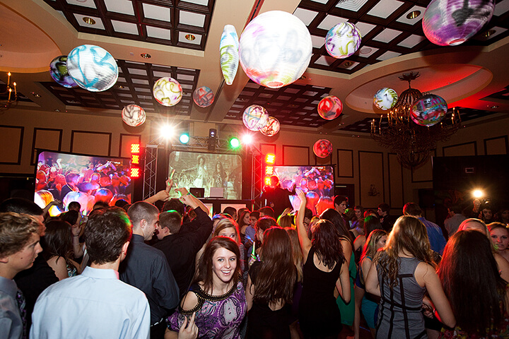 High-energy school dance, students dancing under colorful lights
