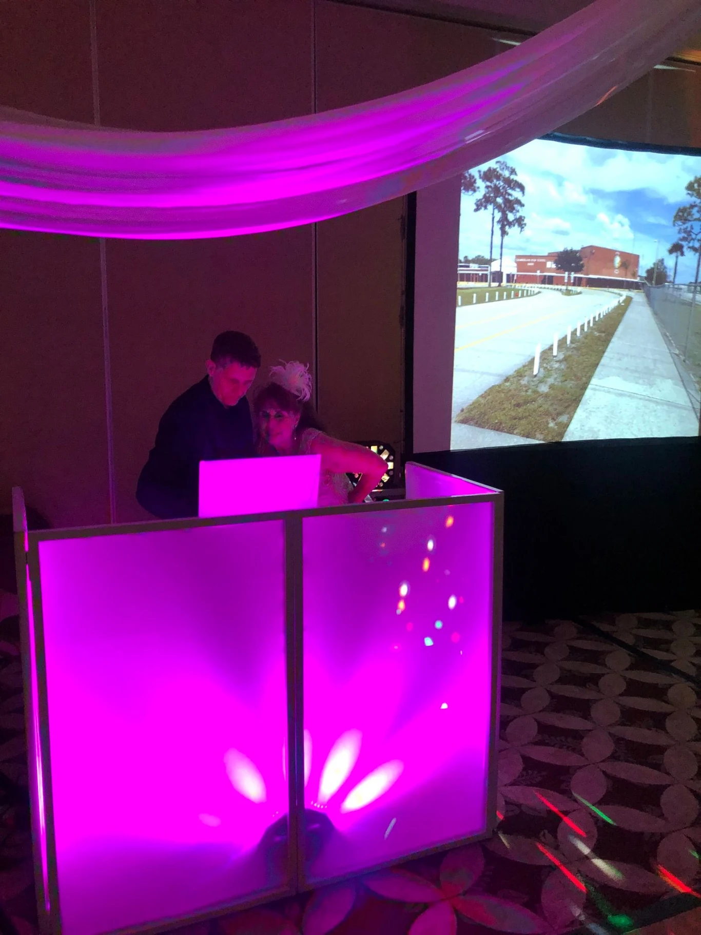 Photo taken of our DJ behind his booth while a party attendee is requesting a song.