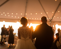 Photo of a newly married couple walking into their wedding reception, taken from behind them.