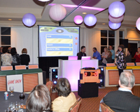 Photo of our "Family Feud" style game in action with ethe screen, busser and family corrals all in place, while the 2 teams are circled around trying to come up with an answer.
