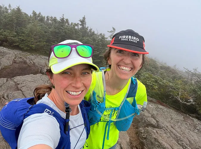 Two smiling Swiftly employees taking a selfie together atop a foggy mountain during a hike.