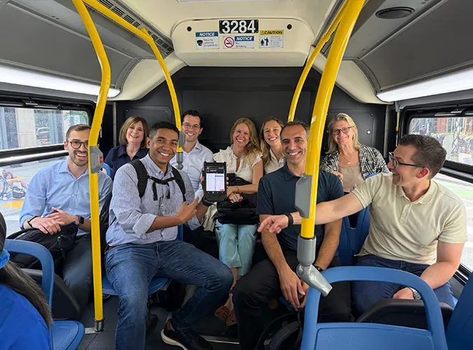 A group of Swiftly employees smiling together while riding a public transit bus.