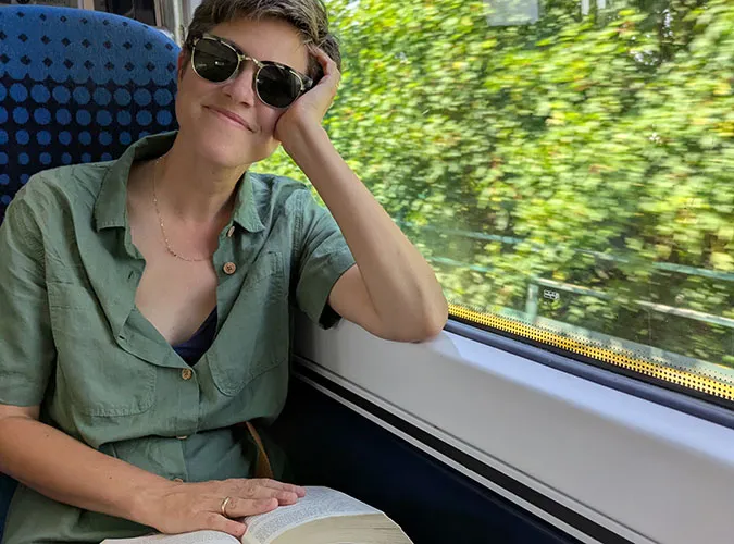 A Swiftly employee reading a book and relaxing while riding a train.