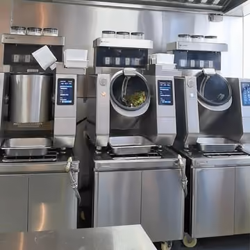 Three fixed automated cooking stations installed side by side in a commercial kitchen