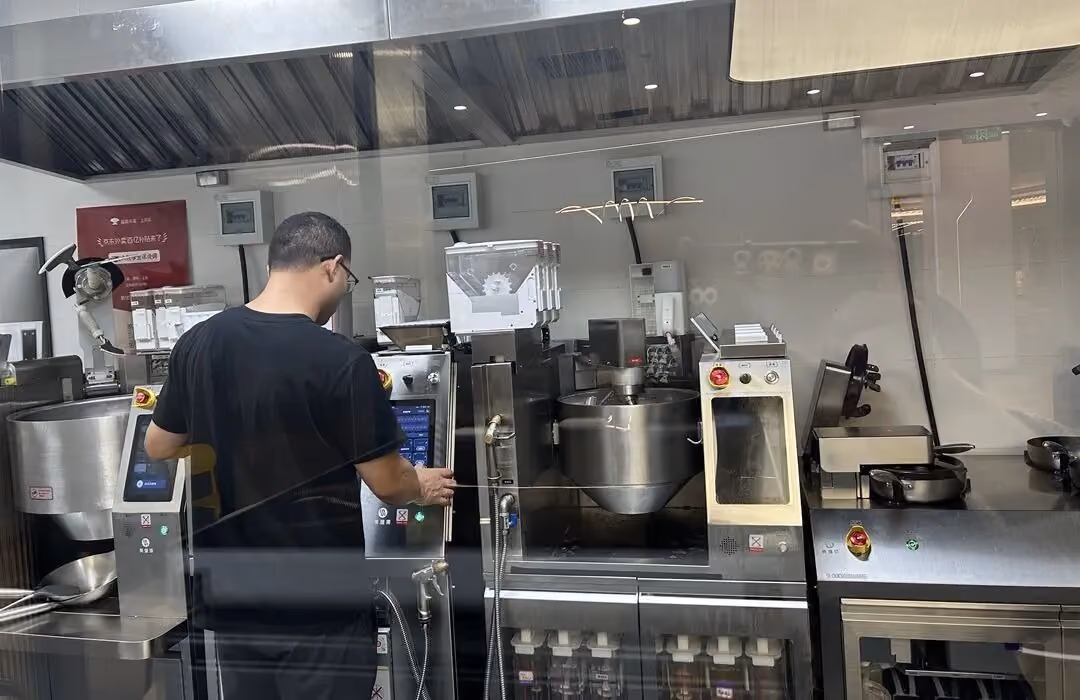 Operator reviewing controls across several fixed commercial cooking stations