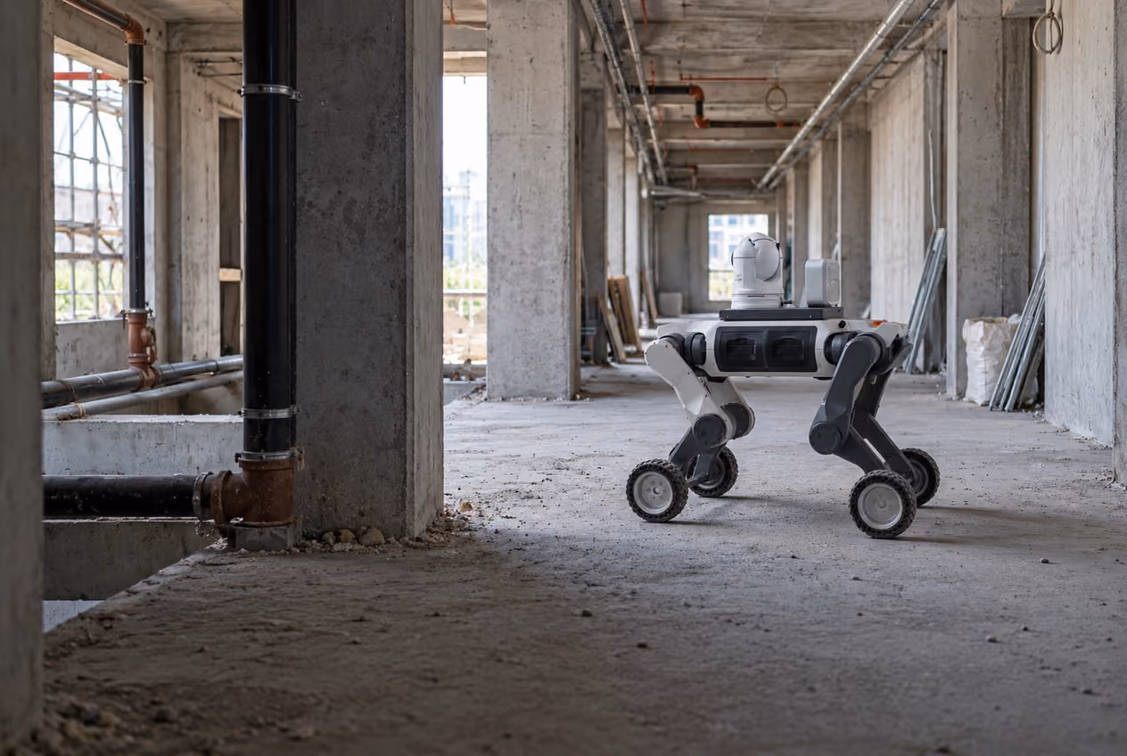 Wheeled quadruped with mounted sensors surveying a clear route on an unfinished construction floor.