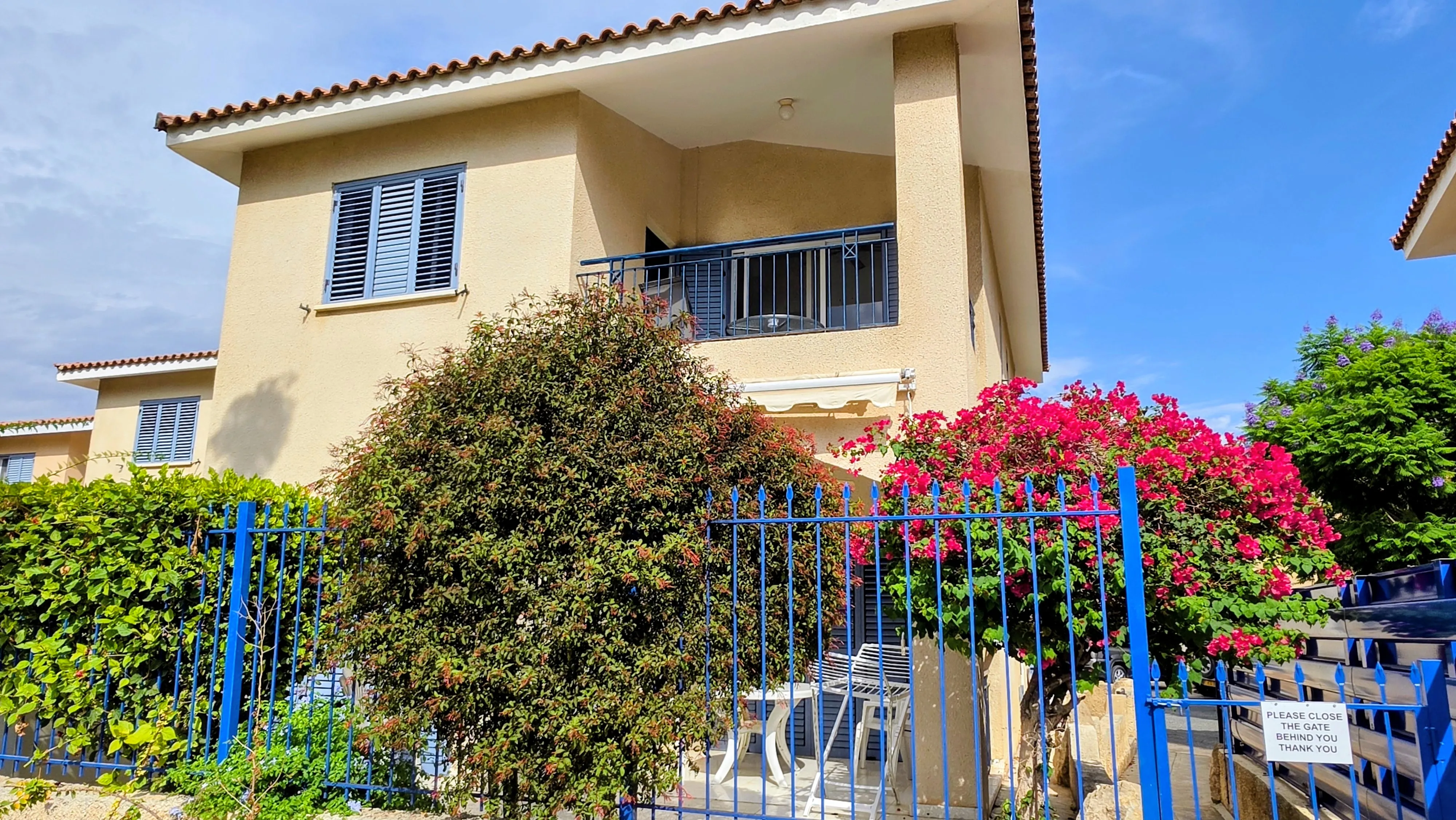 Villa Nadezda seen from the street, with bougainvillea in bloom by the blue gate, Kato Paphos
