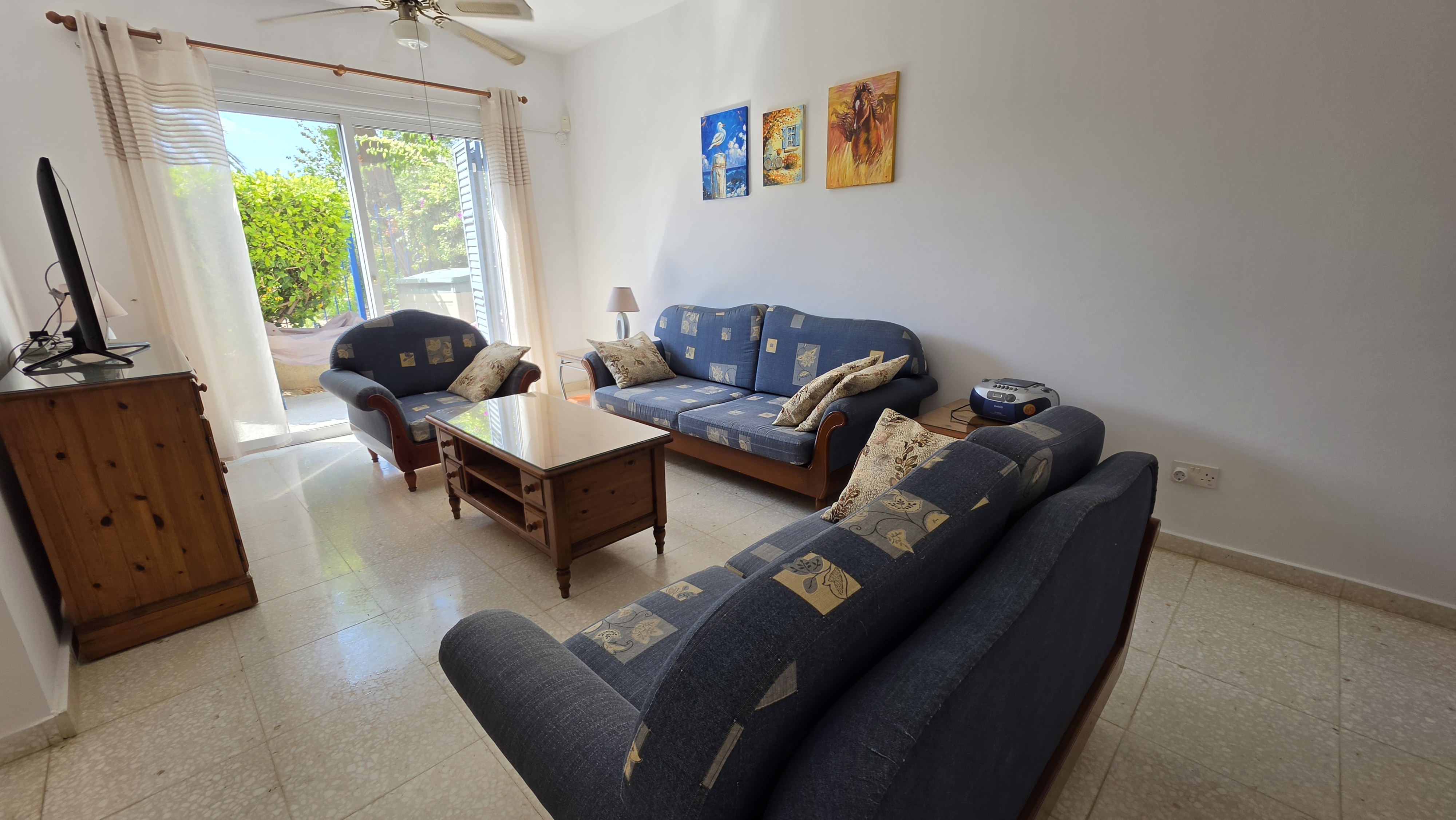 Living room at Villa Nadezda with sofas, television and doors onto the garden, Kato Paphos