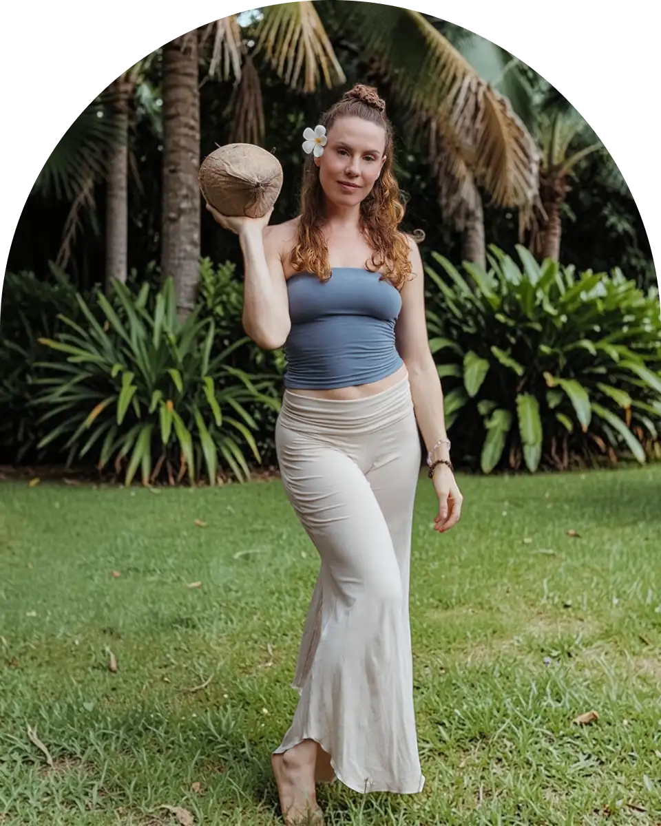 Steph holding a fresh coconut in a tropical garden at Glow Colonics detox and wellness studio