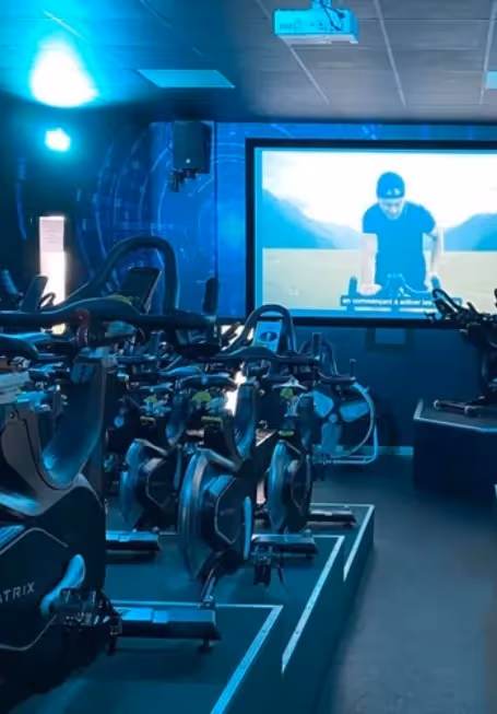 Salle de cycling immersive avec vélos Matrix et grand écran de projection de l'hôtel Ysotop à Grenoble.