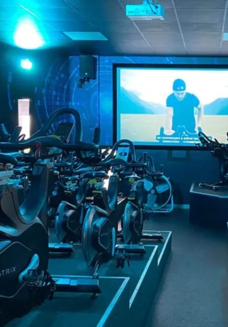 Salle de cycling immersive avec vélos Matrix et grand écran de projection de l'hôtel Ysotop à Grenoble.
