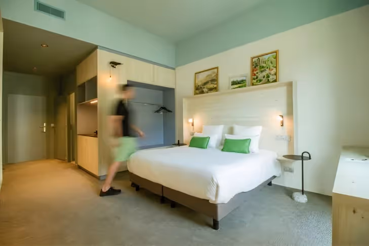 Spacious suite with kitchenette and light wood headboard at the Ysotop aparthotel in Grenoble.