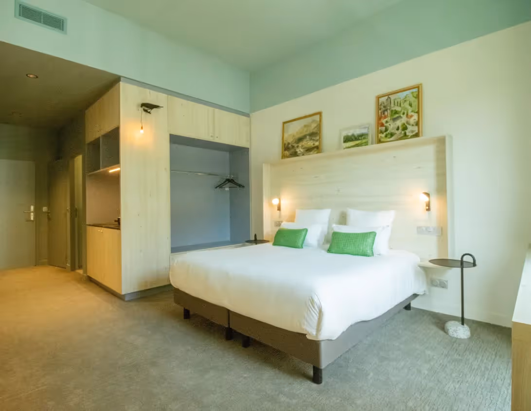 Vue d'ensemble de la chambre classique avec grand lit dressing et kitchenette de l'hôtel Ysotop à Grenoble.