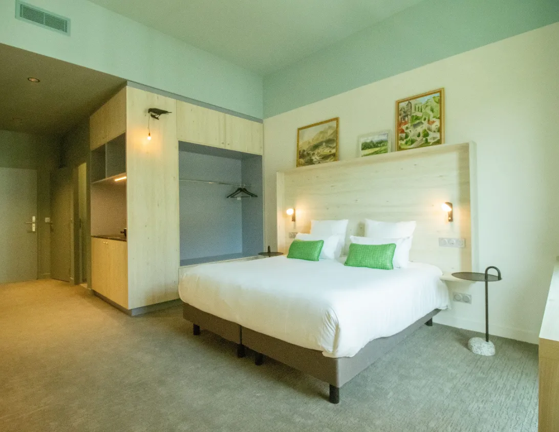 Vue d'ensemble de la chambre classique avec grand lit dressing et kitchenette de l'hôtel Ysotop à Grenoble.