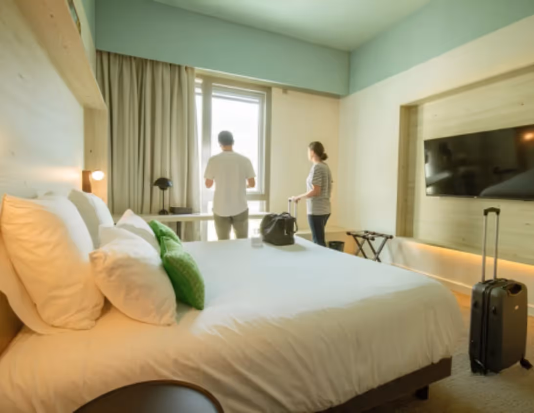 Couple découvrant la chambre classique lumineuse avec TV et grand lit de l'hôtel Ysotop à Grenoble.