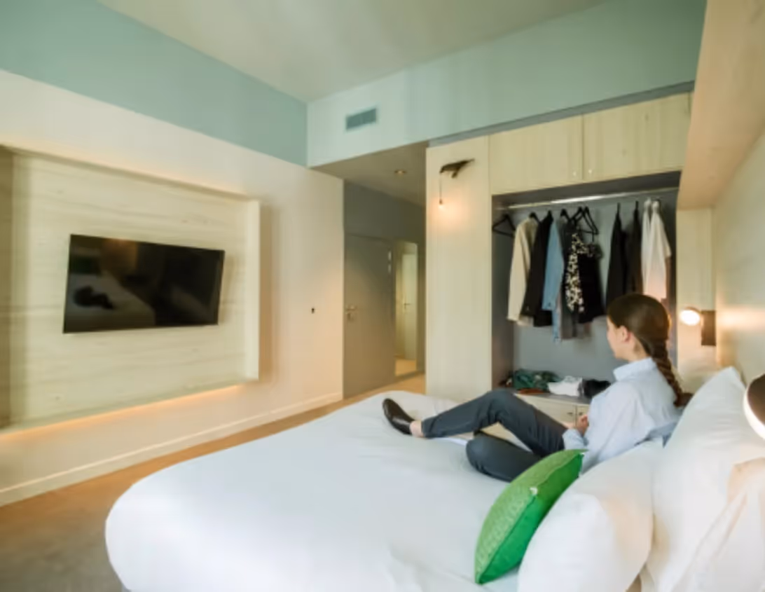 Chambre supérieure avec TV murale dressing ouvert et grand lit de l'hôtel 4 étoiles Ysotop à Grenoble.