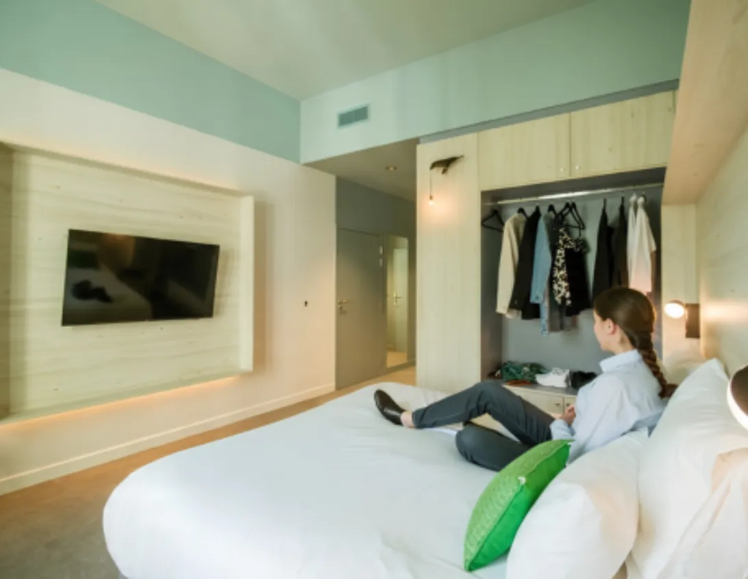 Chambre supérieure avec TV murale dressing ouvert et grand lit de l'hôtel 4 étoiles Ysotop à Grenoble.