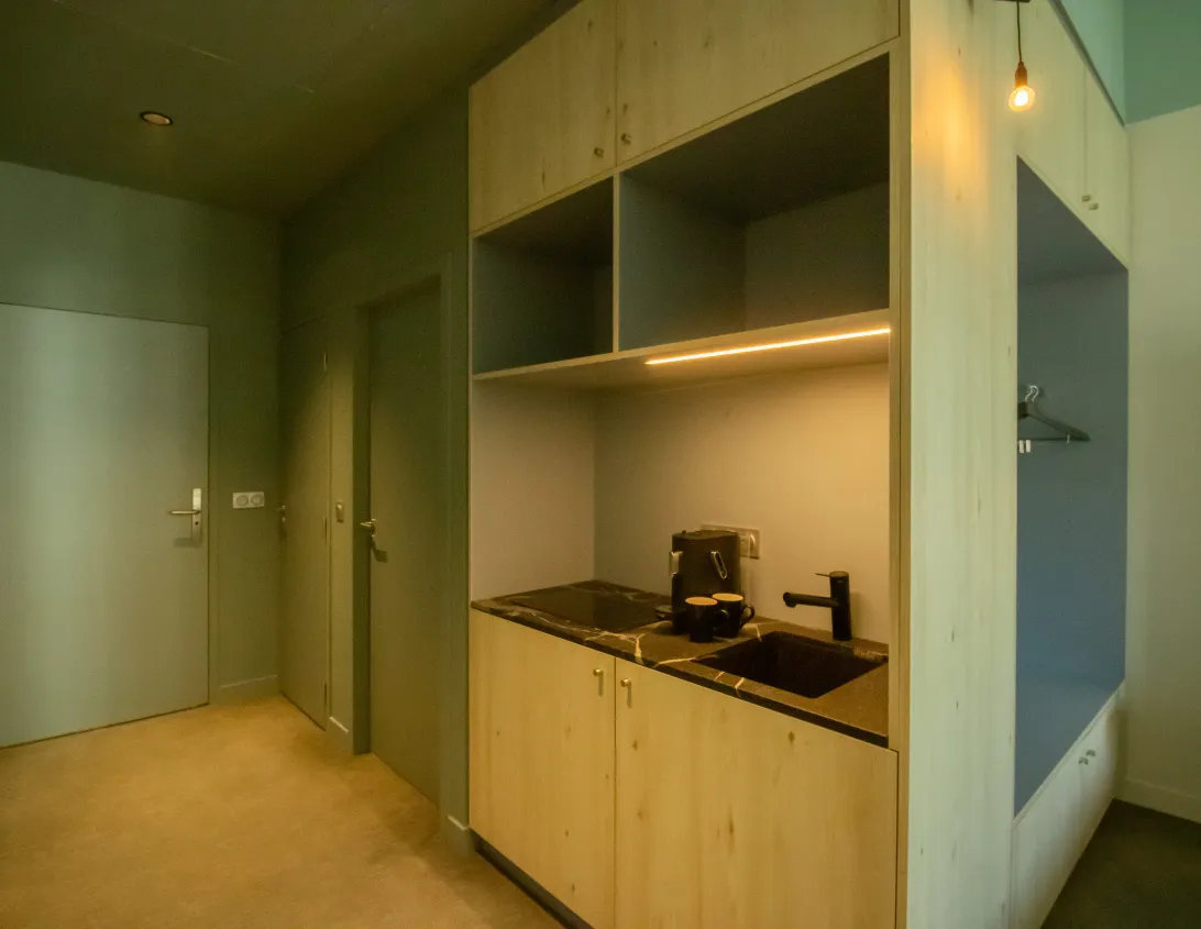 Light wood kitchenette with coffee machine and hob in the Ysotop Grenoble aparthotel studio.