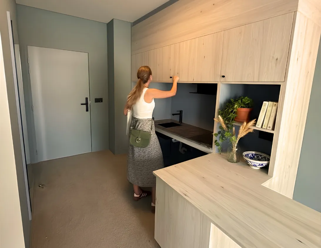 Equipped kitchenette with light wood cupboards and decorated shelves in the large Ysotop Grenoble aparthotel studio.