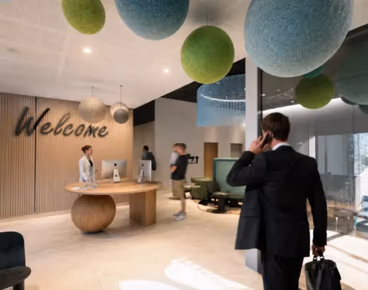 The reception area of the 4-star Ysotop hotel in Grenoble, featuring a 'Welcome' sign and a carved wooden desk.