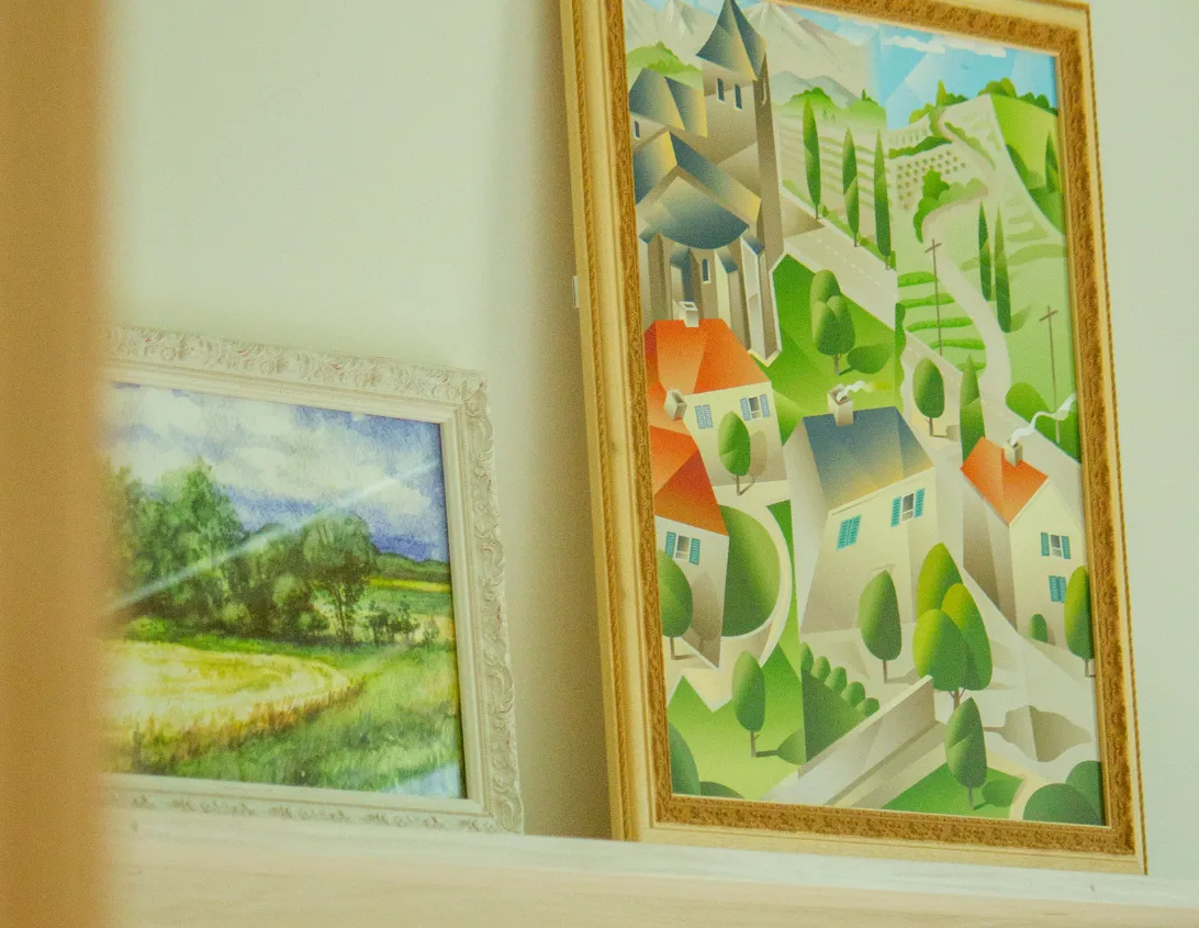 Illustration of an alpine village and rural landscape framed in the large studio of the Ysotop Grenoble hotel.