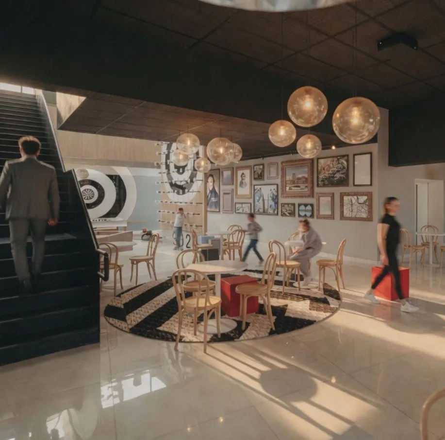 Espace commun animé de l'hôtel Ysotop à Grenoble avec galerie d'art et suspensions dorées au-dessus des tables en rotin.