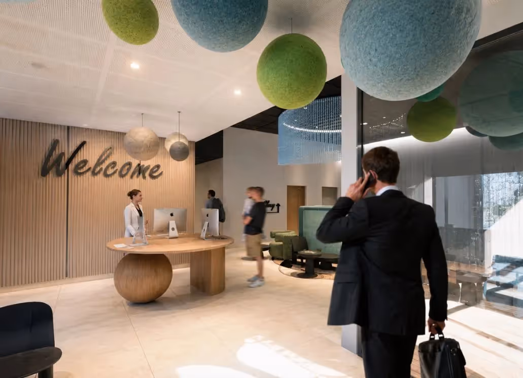 Bright reception area at the Ysotop Hotel in Grenoble, featuring a wooden counter and green and blue pendant lights.