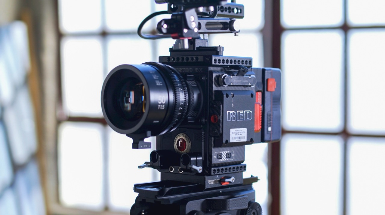 Professional RED digital cinema camera with 50mm T1.5 lens mounted on a tripod indoors near a window.