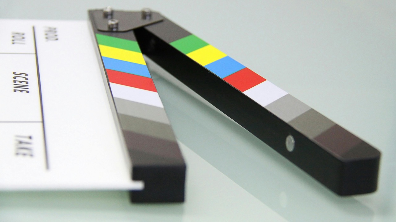 Close-up of a colorful film clapperboard on a reflective surface.