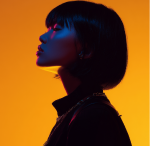 Silhouette of a woman with short hair against an orange background with blue lighting on her face.