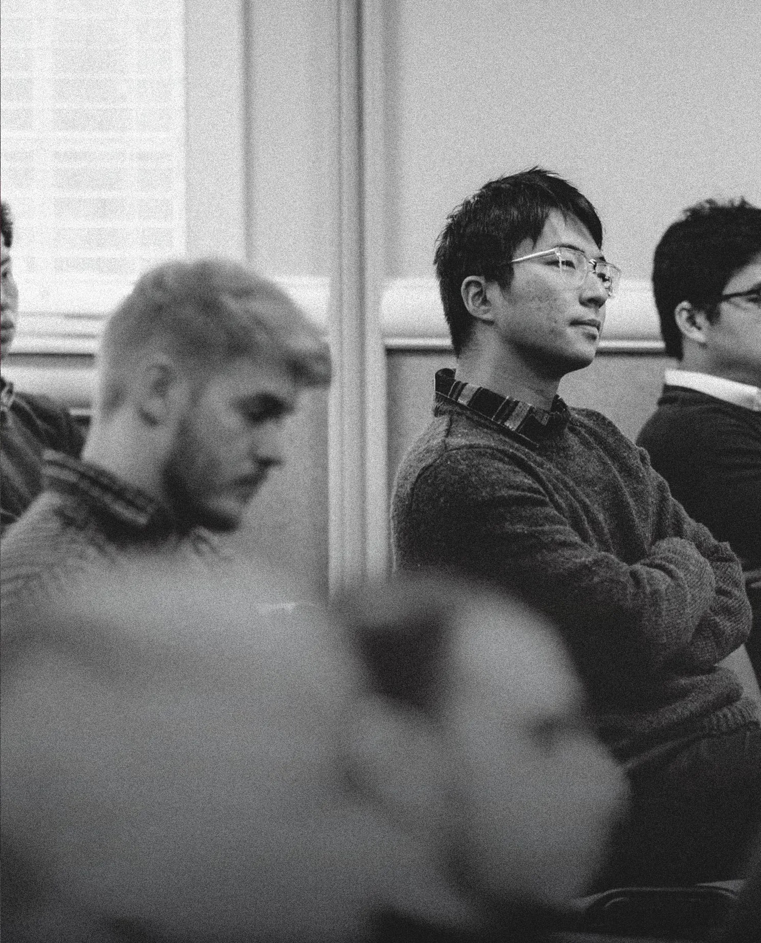 Black-and-white photo of three men sitting attentively in a classroom or meeting setting.
