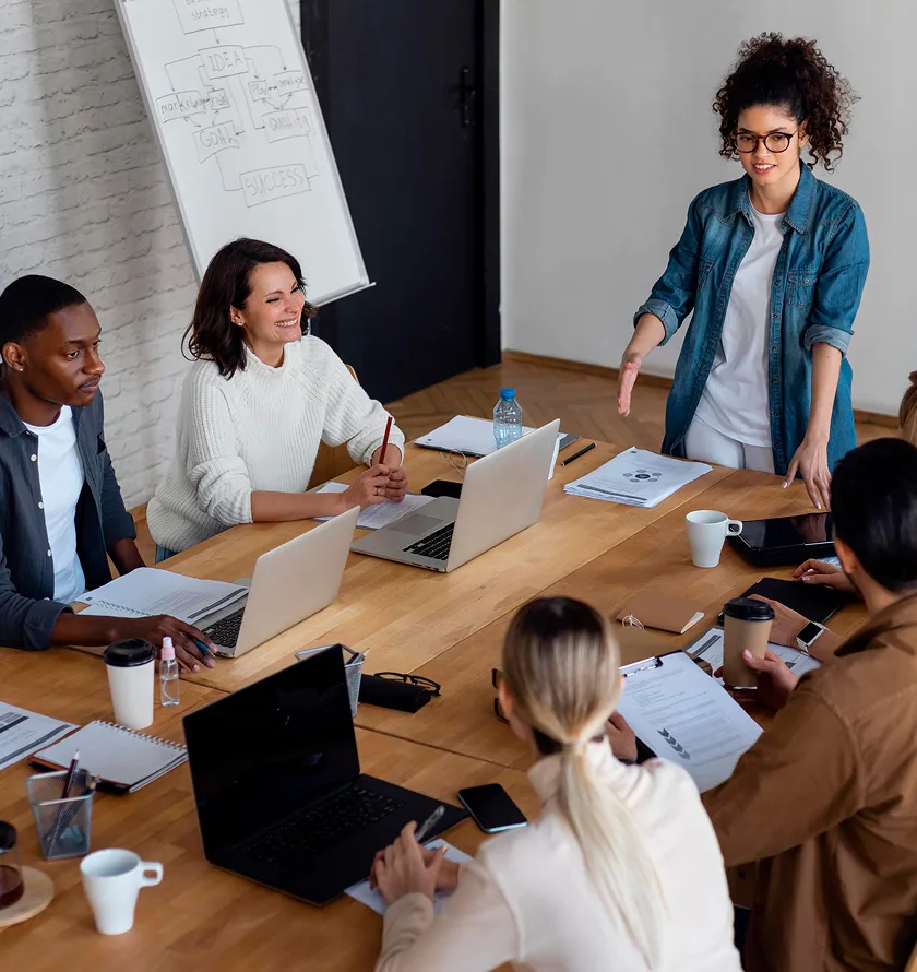 A group of people sitting around a table with laptops.