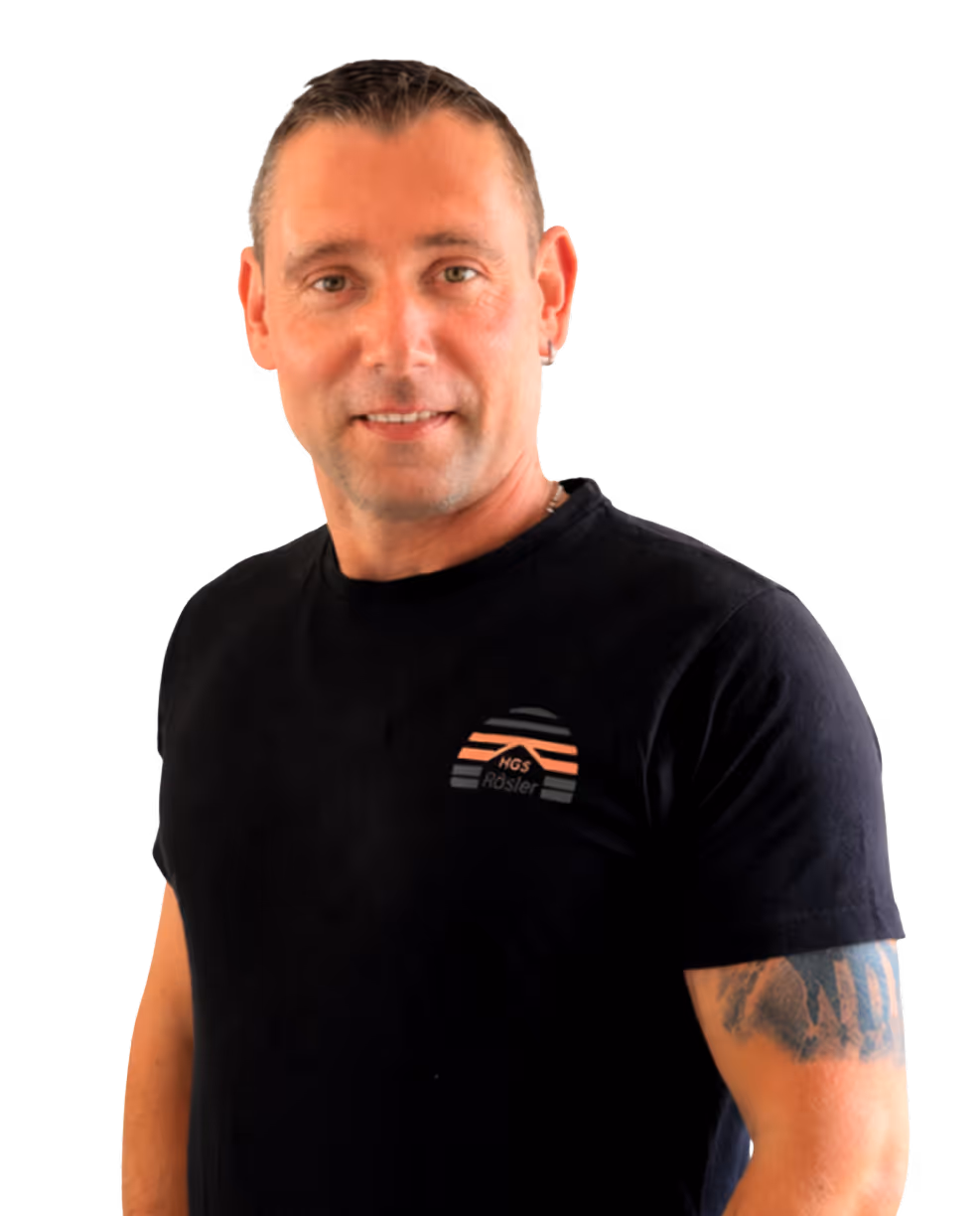 Mann mit kurzen Haaren, schwarzem T-Shirt mit Logo und Tätowierung am rechten Oberarm.