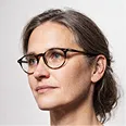 Portrait of a woman with glasses and brown hair tied back, looking slightly to the left.