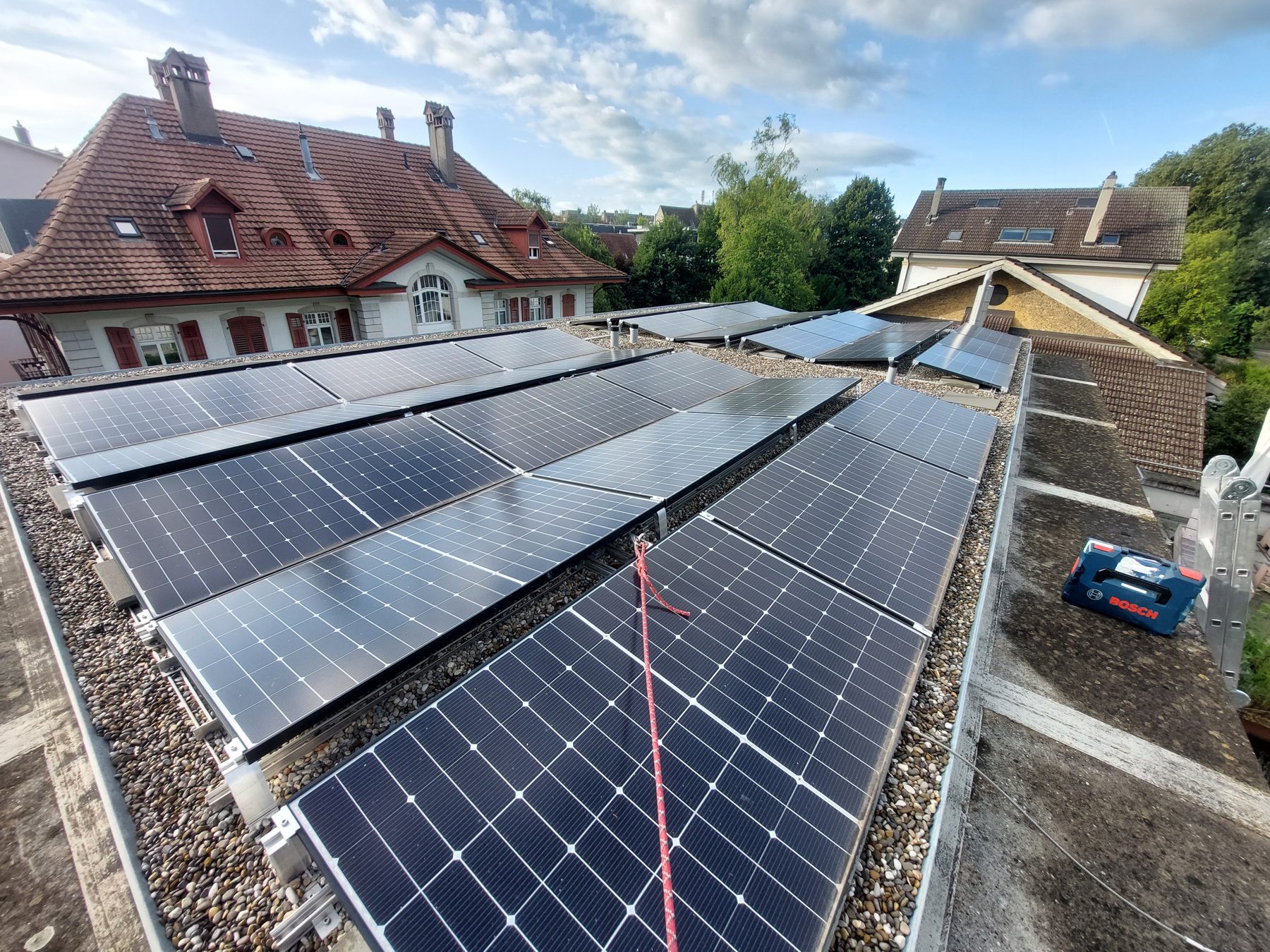 Installation solaire sur un toit plat gravillonné à Bienne, avec les bâtiments anciens du quartier des musées à l'arrière-plan