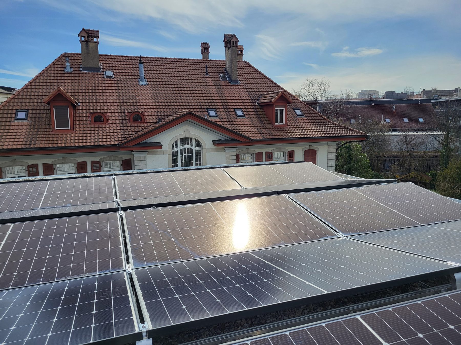 Photovoltaikmodule auf einem Flachdach in Biel vor einem Altbau