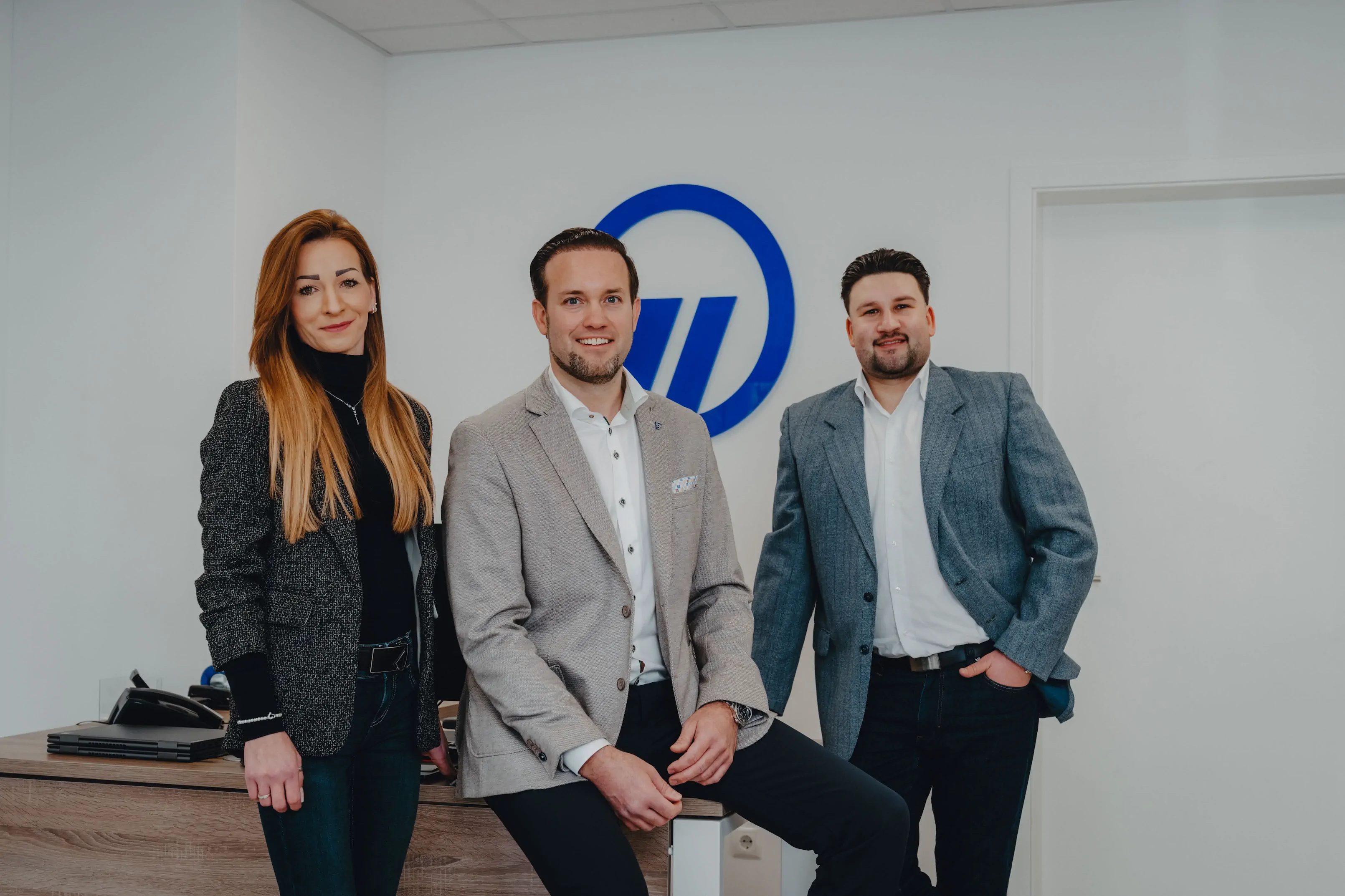 Zwei Männer mit verschränkten Armen stehen vor einer Wand, die mit US-Dollar-Scheinen bedeckt ist.