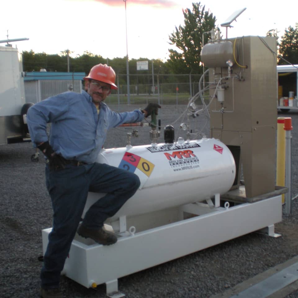 Historical photo of an MRR technician climbing onto a large odorant storage tank, from the company's timeline