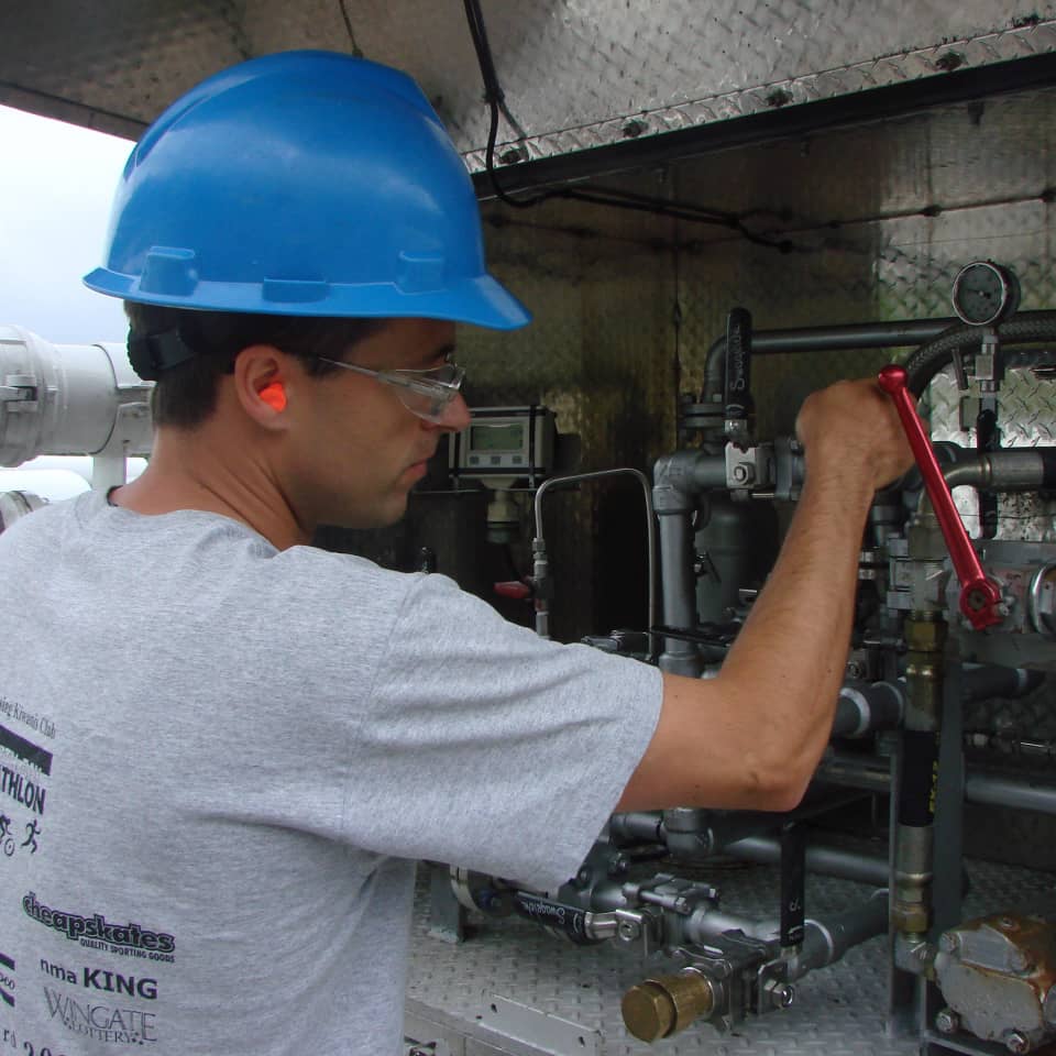 Historical photo of an MRR technician adjusting odorization equipment with a wrench, from the company's timeline